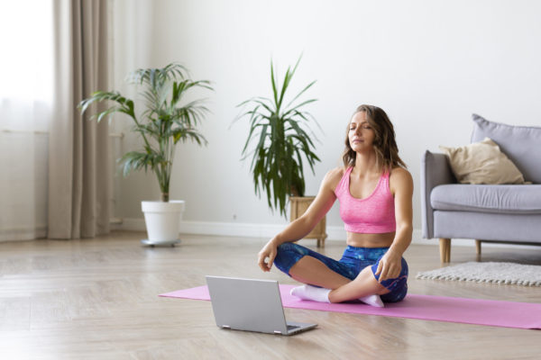 Woman meditate in front of laptop. Woman meditate in front of laptop in hone interior.