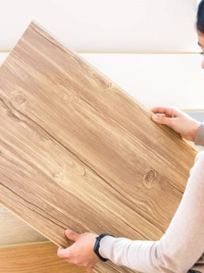 woman choosing wood laminated flooring in shop. home repair.