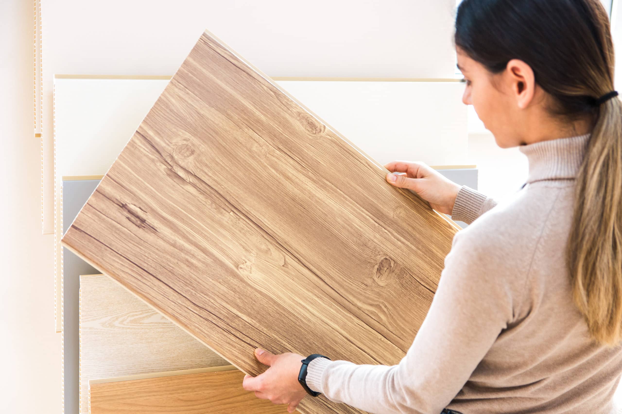 woman choosing wood laminated flooring in shop. home repair.